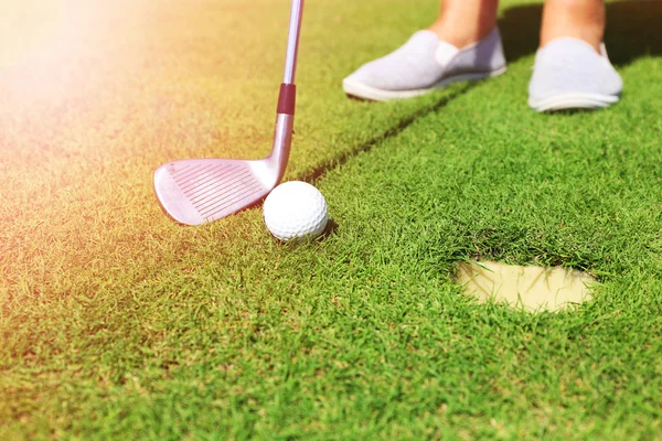 Golfer with club rolls up a ball to the cup on luxury golf course — Stock Photo, Image