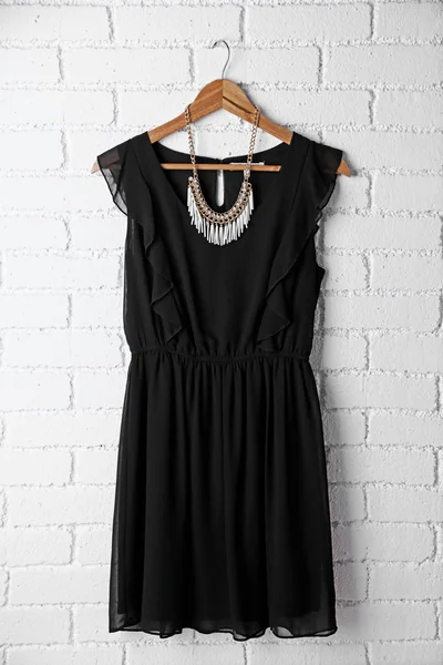 Dress and necklace on hanger on wall background — Stock Photo, Image