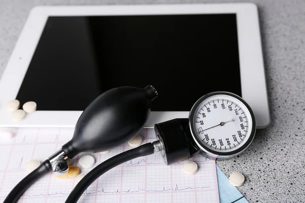 Medidor de pressão arterial, estetoscópio, comprimido digital sobre fundo cinza — Fotografia de Stock