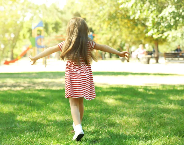 Gelukkig meisje spelen in park in de buurt van de speelplaats — Stockfoto