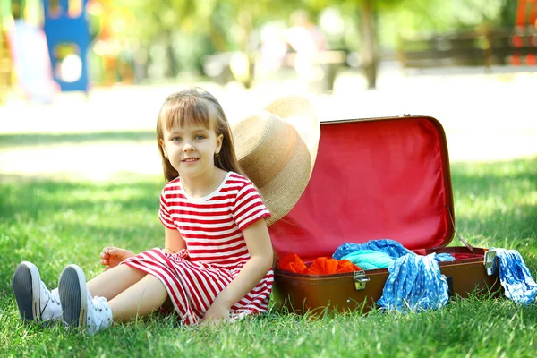 Маленькая девочка с чемоданом в парке — стоковое фото