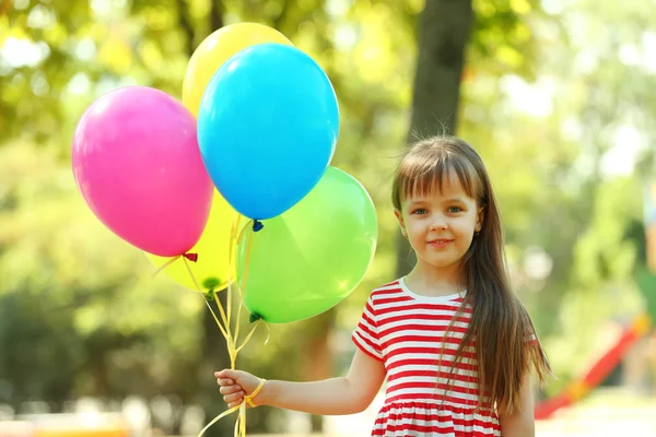 Liten flicka med ballonger i parken — Stockfoto