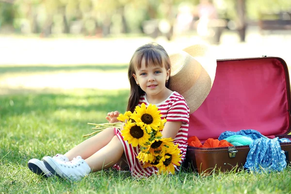 Niña con girasoles y maleta en el parque — Foto de Stock