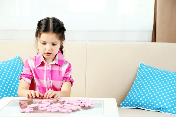 Petite fille mignonne jouant avec des puzzles sur le fond intérieur de la maison — Photo