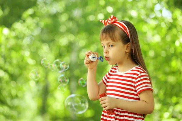 Klein meisje spelen met bubbels in het park — Stockfoto