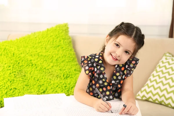 Linda niña haciendo su tarea, primer plano, en el fondo interior del hogar —  Fotos de Stock