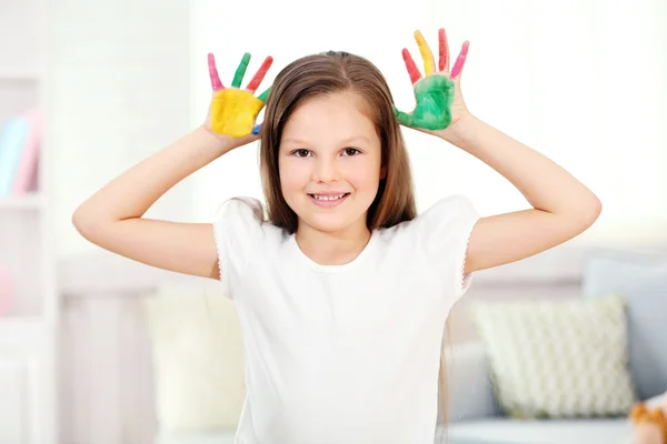 Menina com as mãos na pintura, em casa interior fundo — Fotografia de Stock