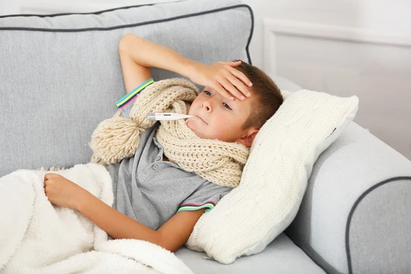 生病的男孩与冷坐在沙发上 — 图库照片