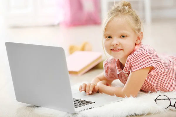 Klein meisje met laptop in de kamer — Stockfoto