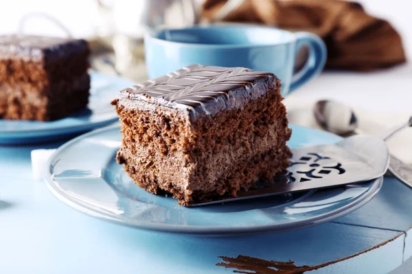 Tavolo servito con una tazza di tè e torte al cioccolato su piatti blu primo piano — Foto Stock