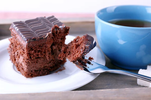 Served table with a cup of tea and chocolate cake on wooden background close-up — Stock Photo, Image