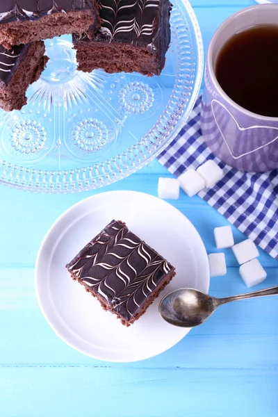 Served table with a cup of tea and chocolate cakes on blue background close-up — Stock Photo, Image