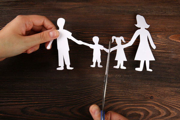 A hand cutting paper chain of a family, divorce and child custody battle