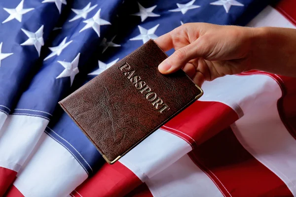 Una mano sosteniendo el pasaporte en el fondo de la bandera americana — Foto de Stock