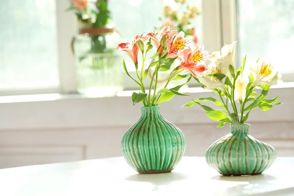 Schöne Alstroemeria-Blumen in Aquamarin-Vasen auf Fensterhintergrund — Stockfoto