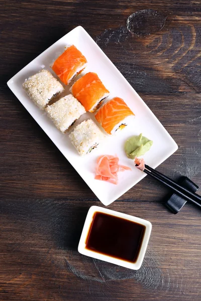 Delicious rolls, ginger, wasabi and soy sauce on wooden background — Stock Photo, Image