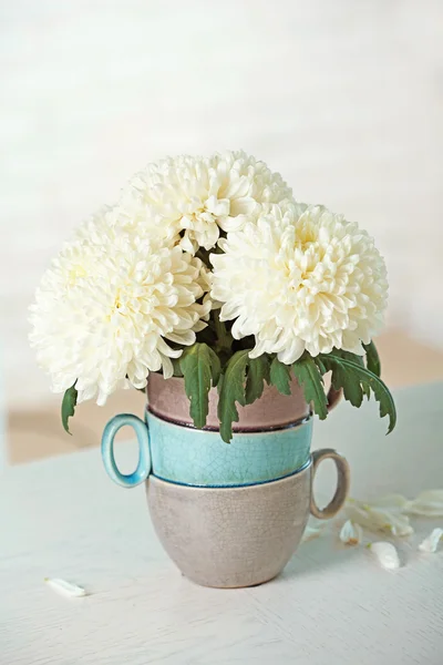 Hermosas flores en jarrón en la mesa en la habitación sobre fondo brillante — Foto de Stock