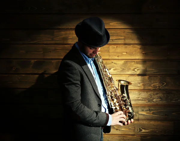 Elegantní saxofonista hraje jazz na dřevěné pozadí — Stock fotografie