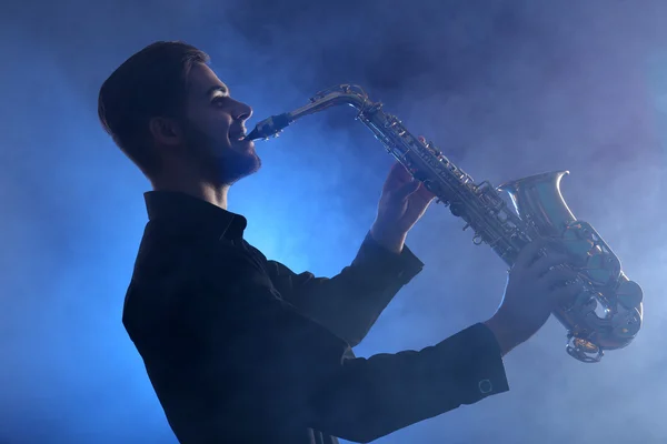 Saxofonista elegante toca jazz na fumaça azul — Fotografia de Stock