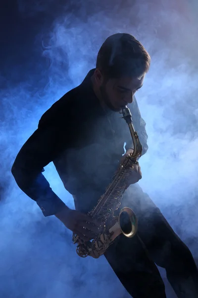 Saxofonista elegante toca jazz na fumaça azul — Fotografia de Stock