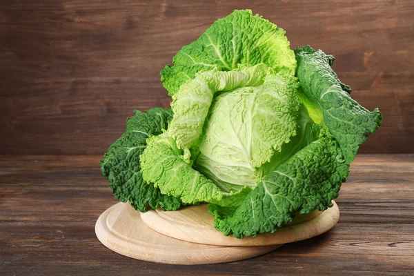 Savoy cabbage on cutting board on wooden background — Stock Photo, Image