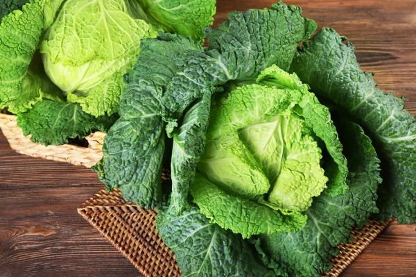 Savoy cabbage in wicker basket on wooden background — Stock Photo, Image