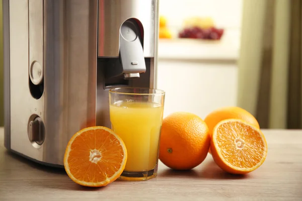 Juicer y jugo de naranja en la mesa de la cocina — Foto de Stock