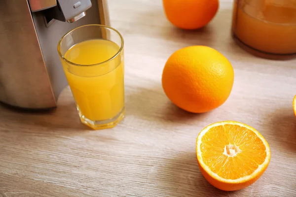 Mutfak masasının üzerinde meyve sıkacağı ve portakal suyu — Stok fotoğraf