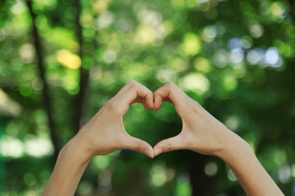 Handen in de vorm van liefde hart op aard achtergrond — Stockfoto