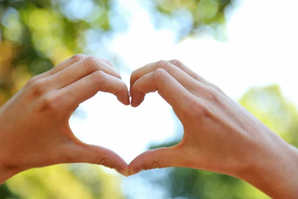 Handen in de vorm van liefde hart op aard achtergrond — Stockfoto