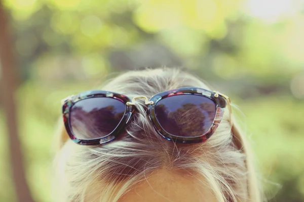 Glasses on head of  girl on nature background — Stock Photo, Image