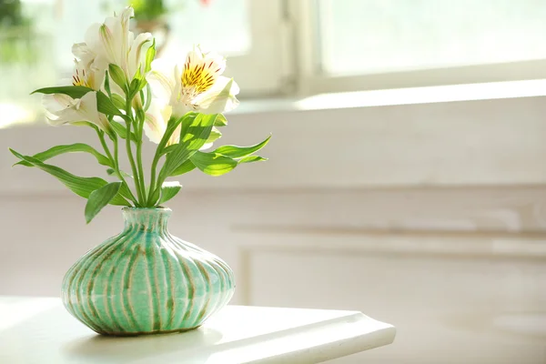 Beautiful Alstroemeria flowers in aquamarine vases on window background Stock Photo