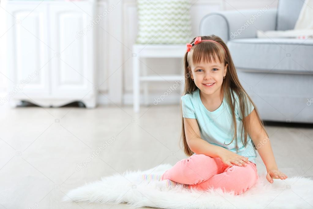 Cute niña sentada en la alfombra, en el fondo interior casa — Foto de