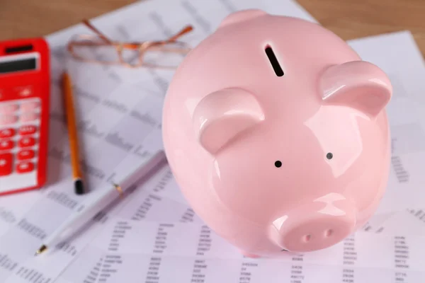 Pig moneybox and calculating equipment on desk closeup — Stock Photo, Image