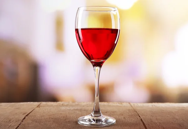 Red wine glass on wooden table against unfocused background — Stock Photo, Image