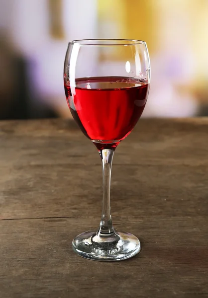 Red wine glass on wooden table against unfocused background — Stock Photo, Image