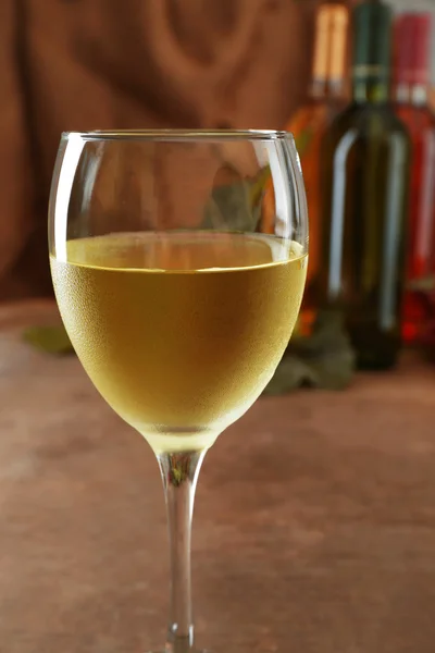 Witte Wijnglas tegen verschillende flessen en druivenmost op houten tafel — Stockfoto