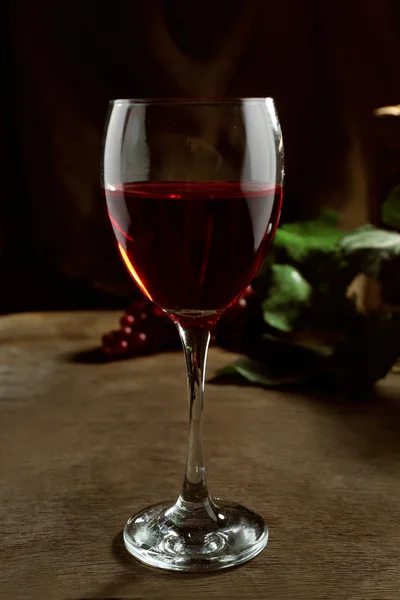 木製テーブルの上のブドウとワインのボトルの枝編み細工品バスケットに対して赤ワインのガラス — ストック写真