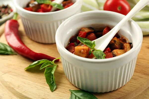 Gustosa ratatouille vegetariana fatta di melanzane, zucca, pomodori in ciotole su sfondo tavolo di legno — Foto Stock