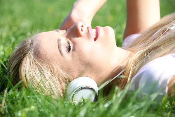 Jonge vrouw in oortelefoons op gras — Stockfoto