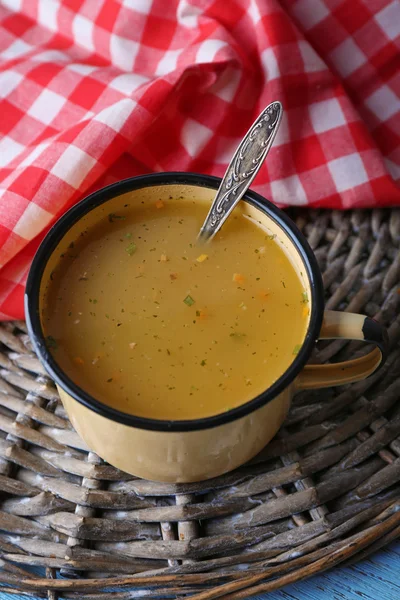 Mug of soup on wicker mat on a table closeup — Stock Photo, Image