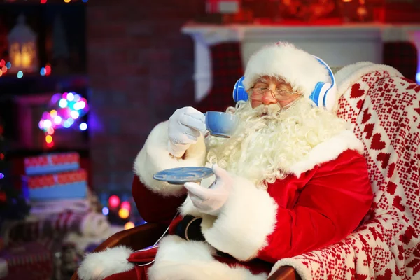 Santa Claus sitting with headphones sitting in comfortable rocking chair at home — Stock Photo, Image