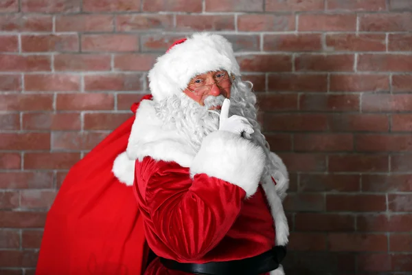 圣诞老人与袋，填充上砖的背景墙上的礼品盒 — 图库照片