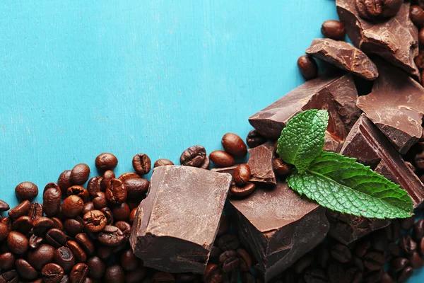 Siyah çikolata parçaları ve renk ahşap arka plan üzerinde kahve taneleri — Stok fotoğraf