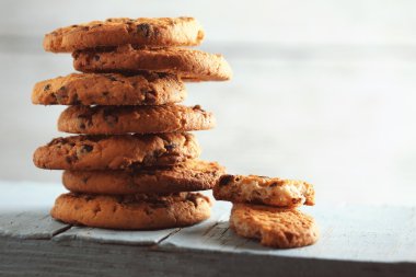 Bulanık bir arka plana dayanır, mavi ahşap masa üzerinde çikolata kırıntıları ile çerezleri kapatmak