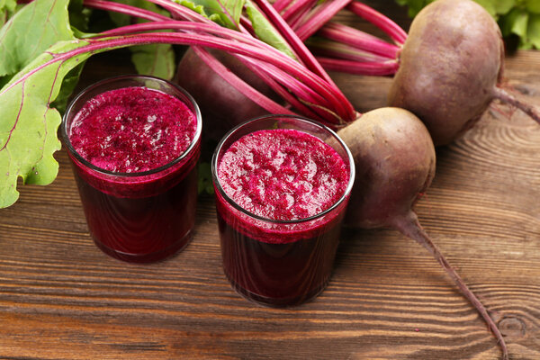 Glasses of beet juice with vegetables on table close up