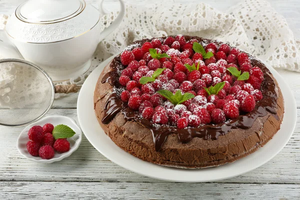 Cake with Chocolate Glaze and raspberries and cup of tea on color wooden background — Stock Photo, Image