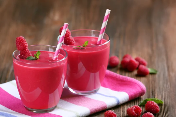 Glazen raspberry milkshake met bessen op houten tafel close-up — Stockfoto