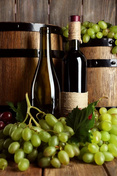 白と赤の木製の背景にワインのボトルとブドウ — ストック写真