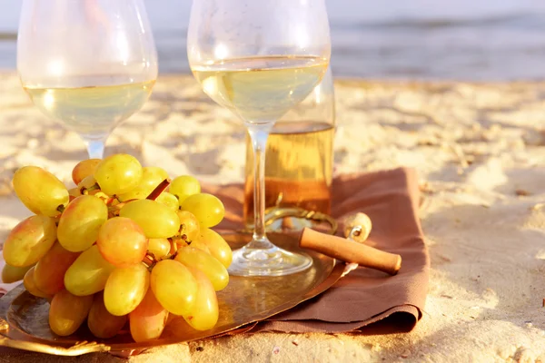 Романтический состав белого вина и винограда на песчаном пляже — стоковое фото